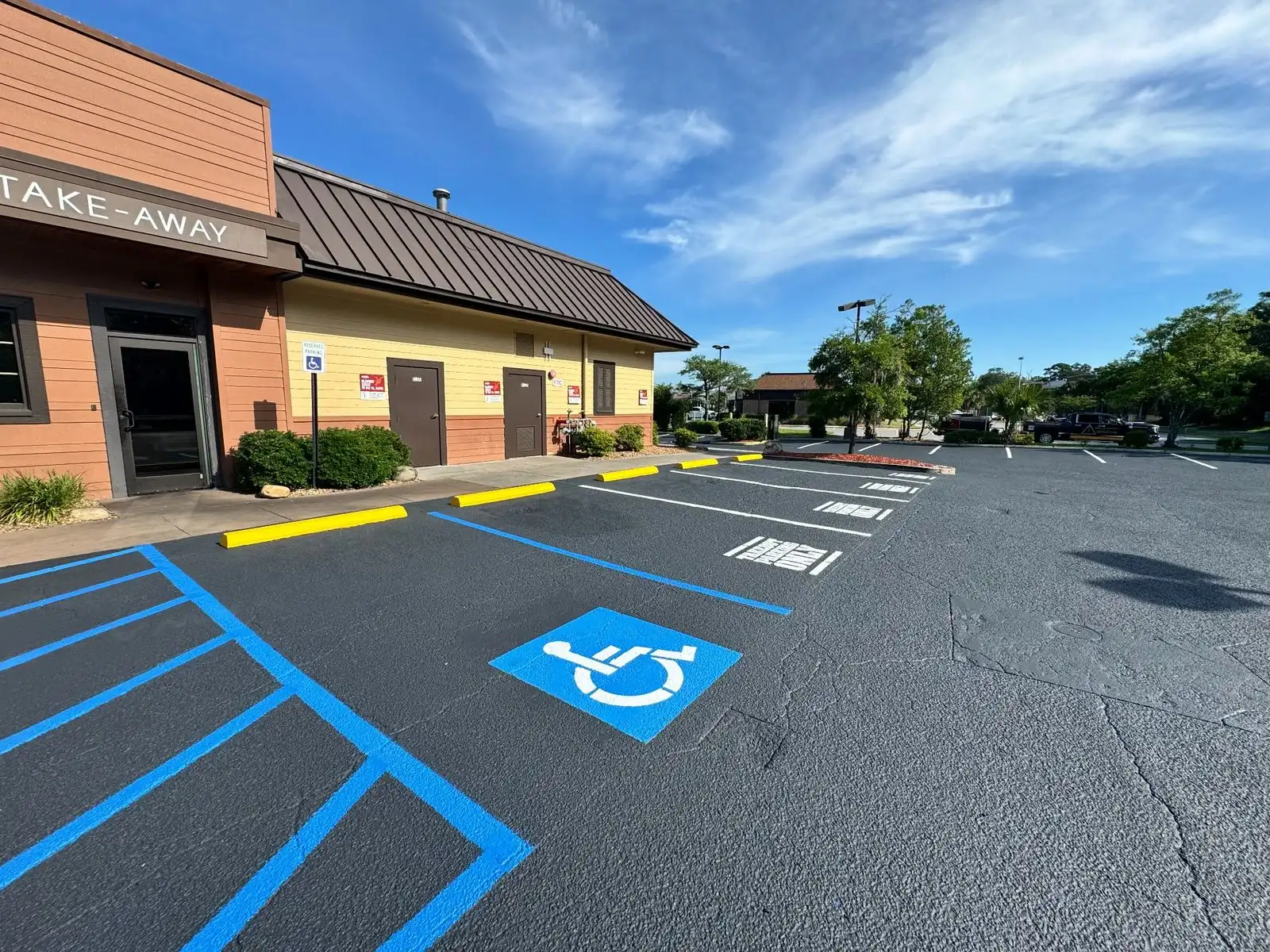 ADA accessible parking space with blue access aisle, accessibility symbol and wheel stops