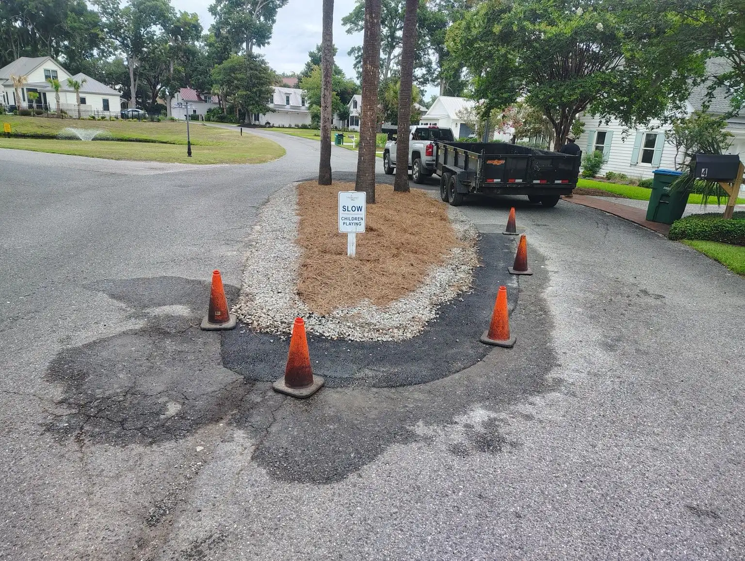 Asphalt patching around a landscaped island on a neighborhood street