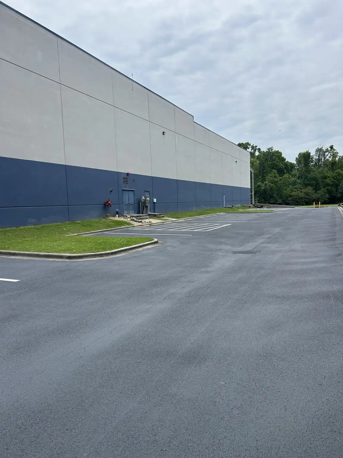 Parking lot striping beside a large commercial warehouse building