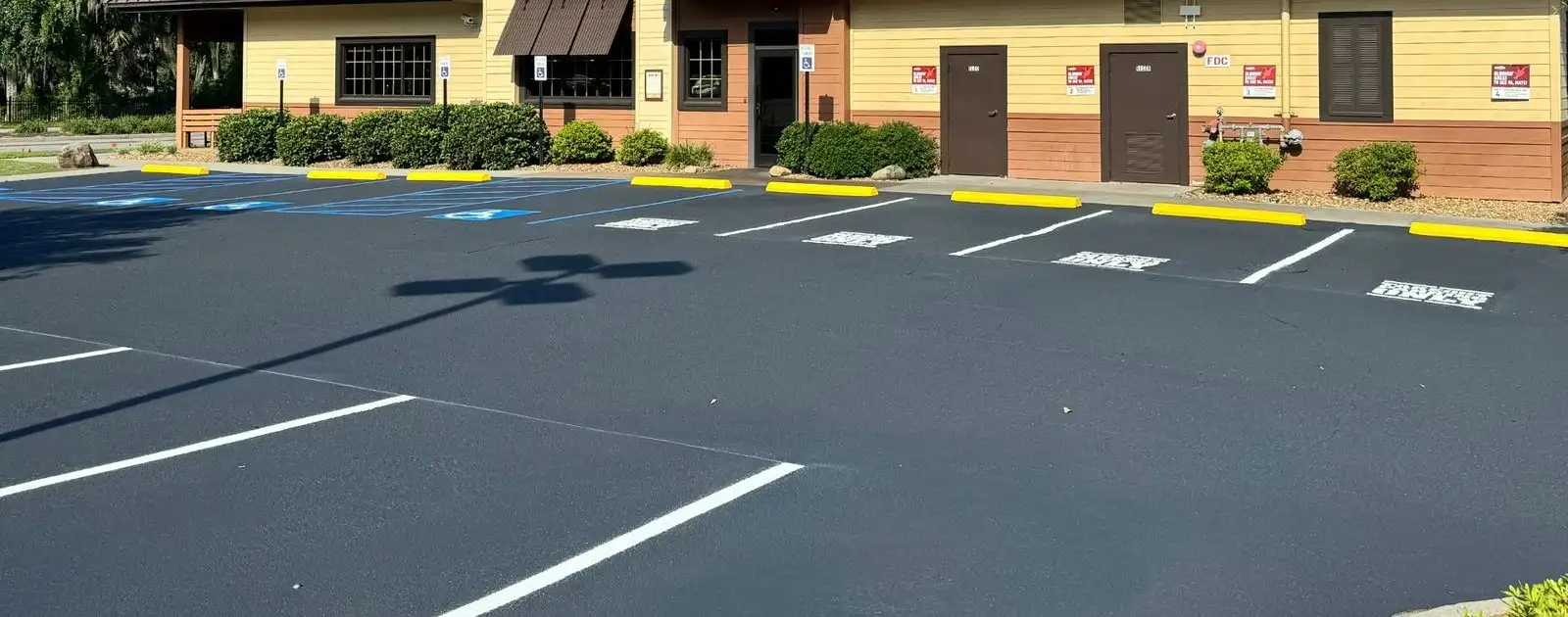 Restaurant parking lot with yellow wheel stops after sealcoating and restriping