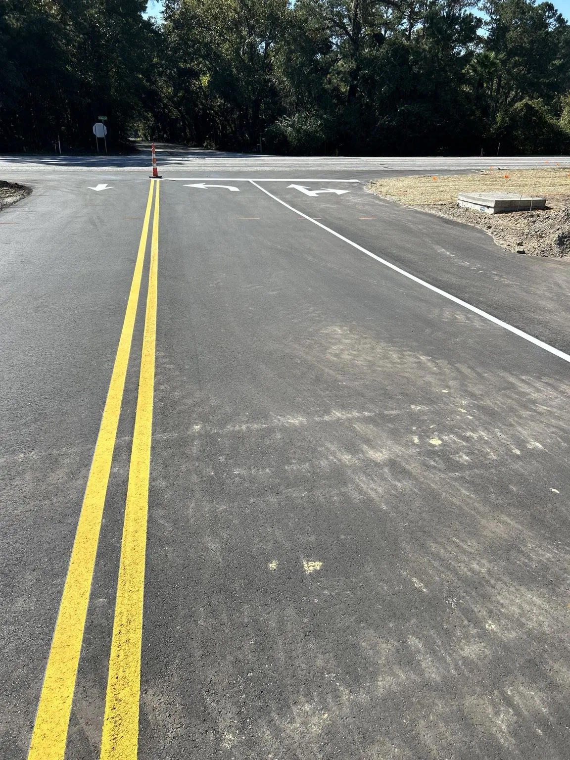 New asphalt roadway with double yellow centerline and arrows