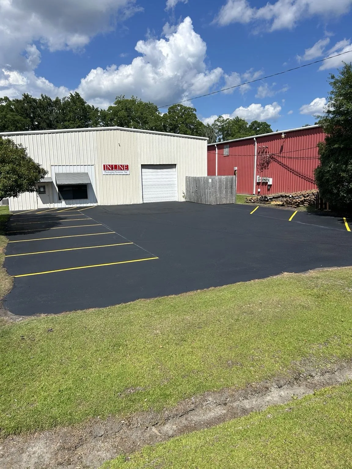 Sealcoated commercial lot with yellow parking stall lines at a warehouse
