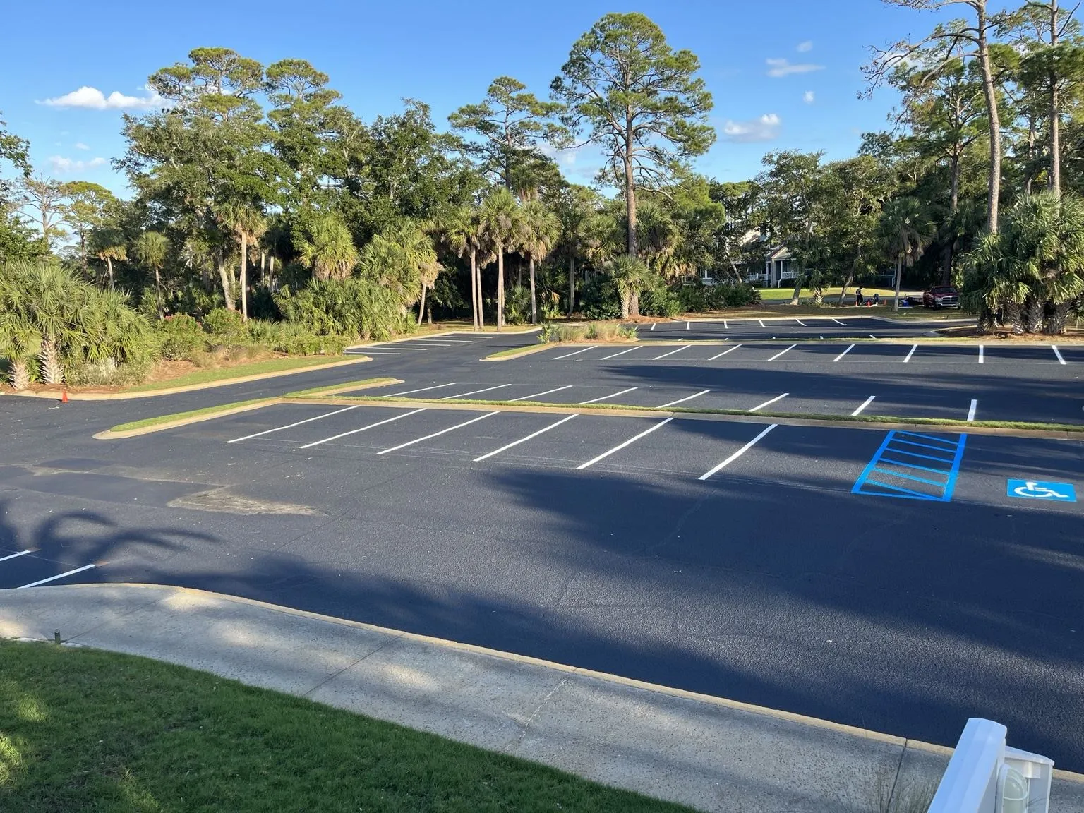 Large commercial parking lot after sealcoating and restriping with white stalls and a blue ADA access aisle